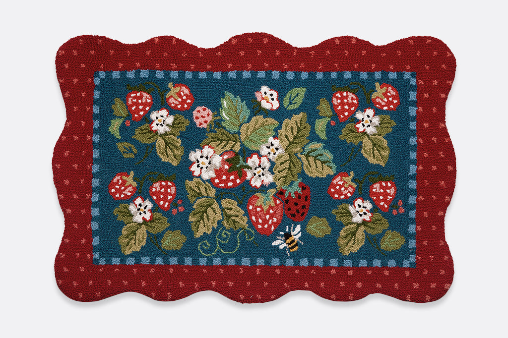 A hooked rug with details of strawberries, flowers, and bees.