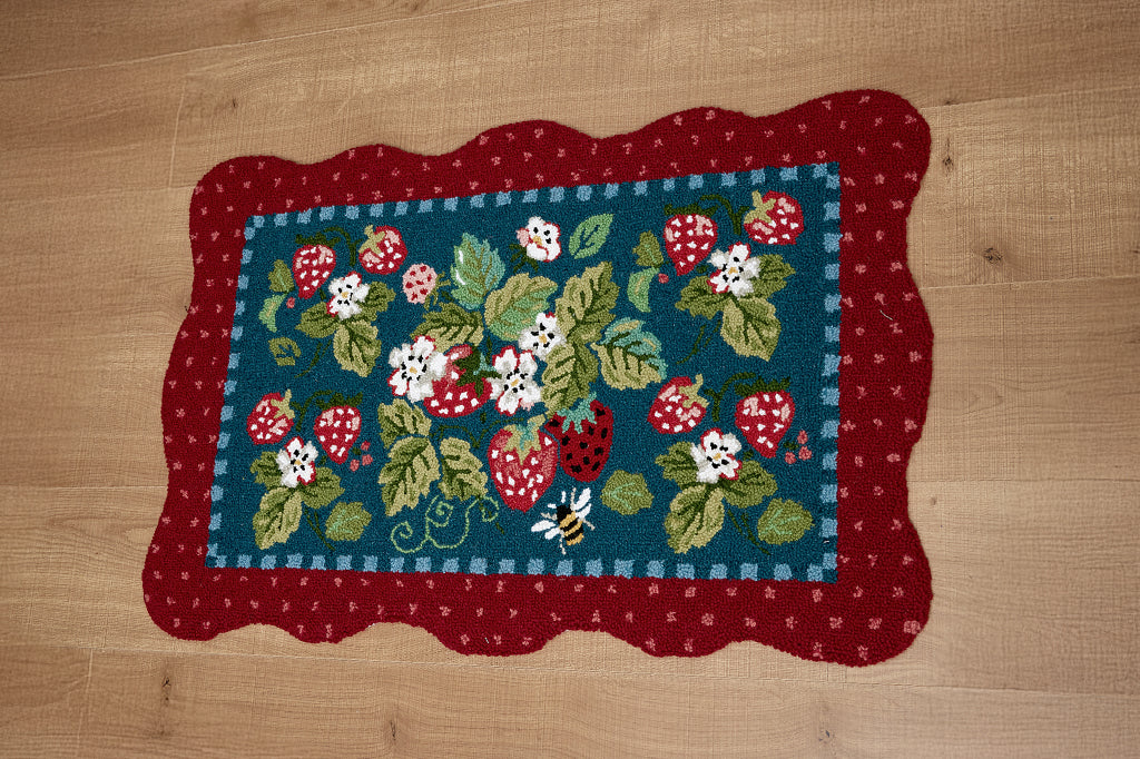A hooked rug with details of strawberries, flowers, and bees.