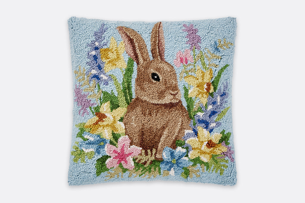 Decorative pillow with a bunny and floral design on a light blue background