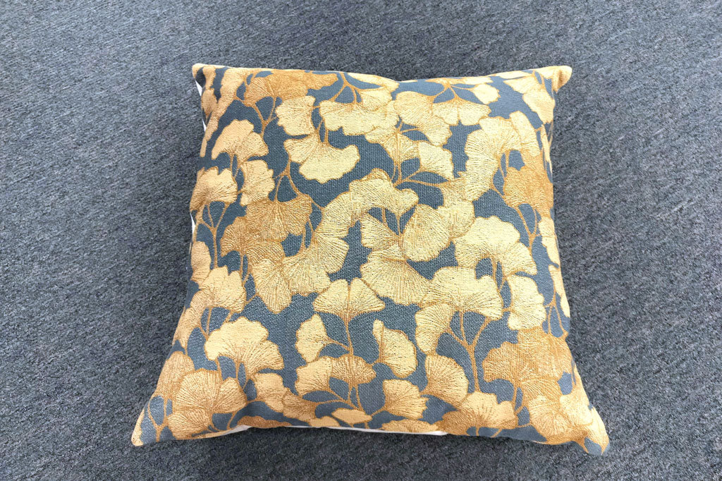 Decorative pillow with golden ginkgo leaf pattern on a slate blue background