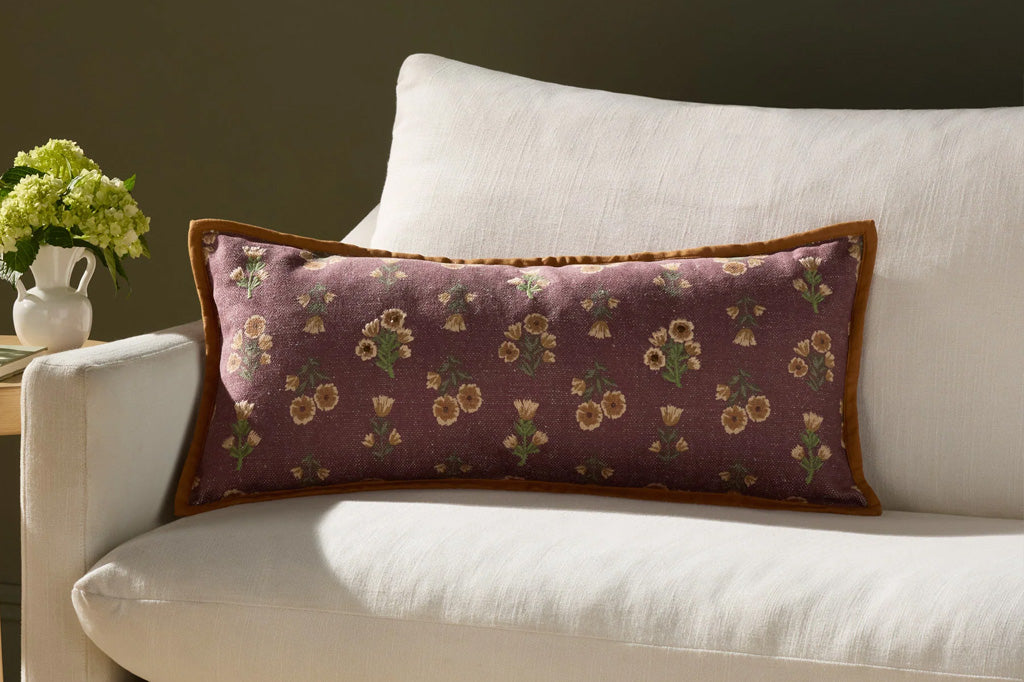 A dark reddish brown pillow with yellow and green flower patterns.