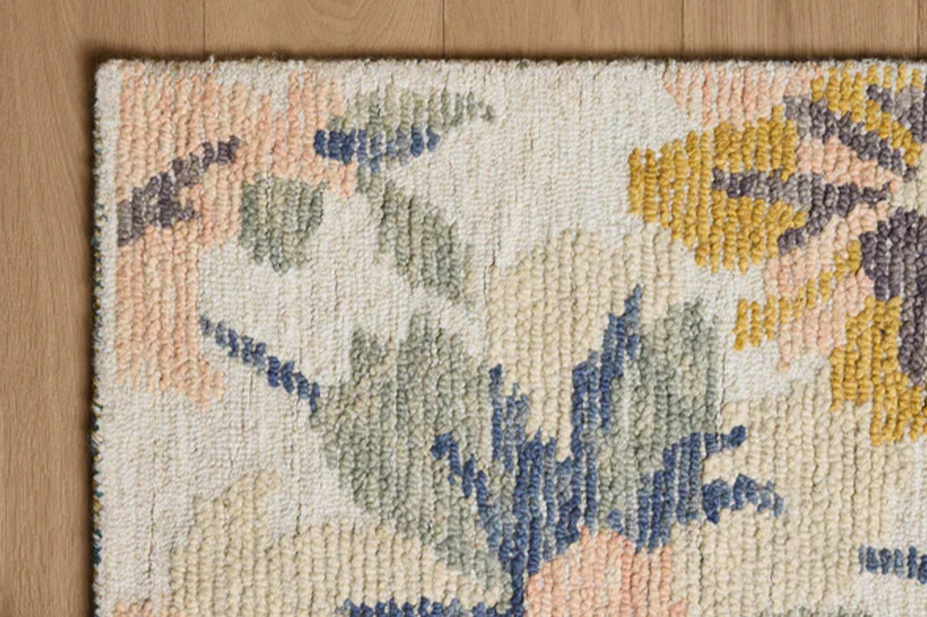 Close-up of a textured rug with floral patterns on a wooden floor.