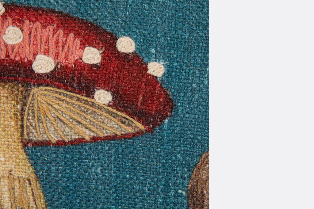 Close-up of a textile art piece with a red mushroom on a blue background