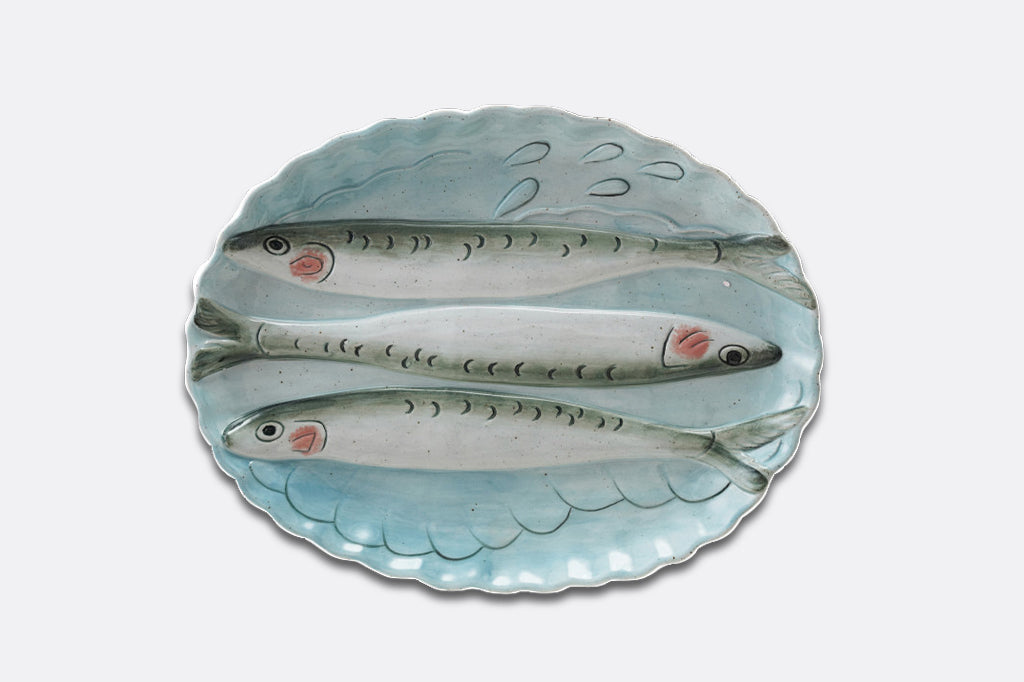 A light blue oval dish with three sardine fish illustrations.
