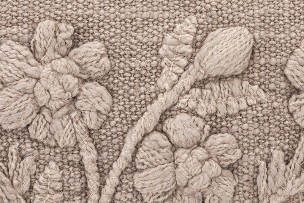 A pillow with illustrations of flowers, dandelions, and dragonflies.
