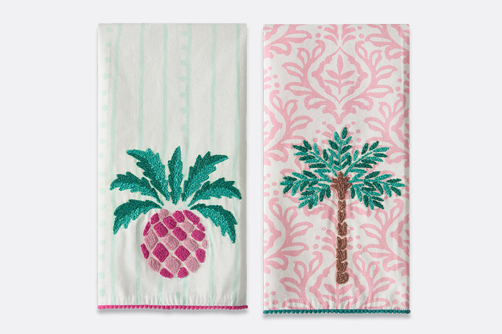 Vibrant pink and green towels with images of pineapples and palm trees.