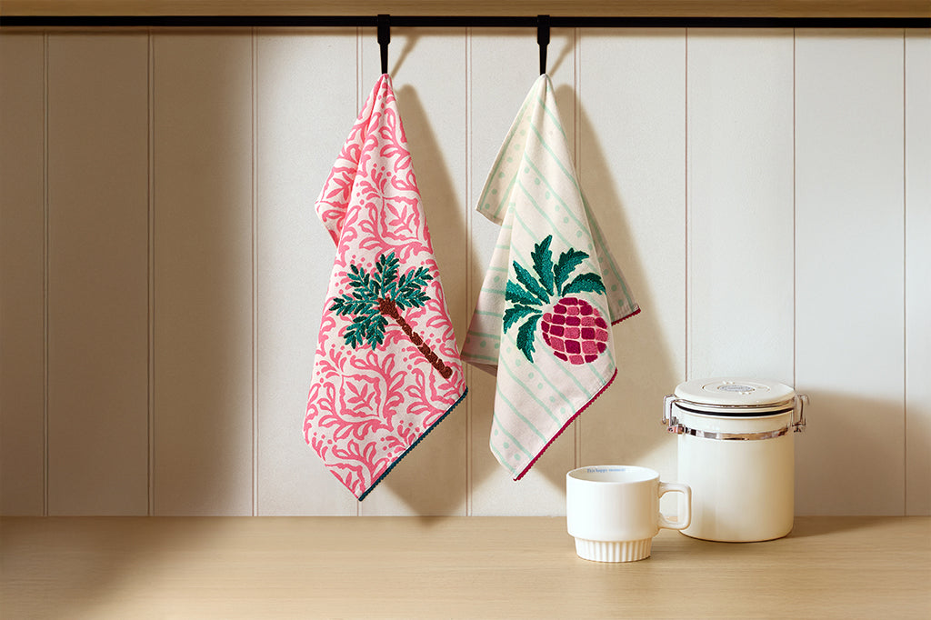Vibrant pink and green towels with images of pineapples and palm trees.