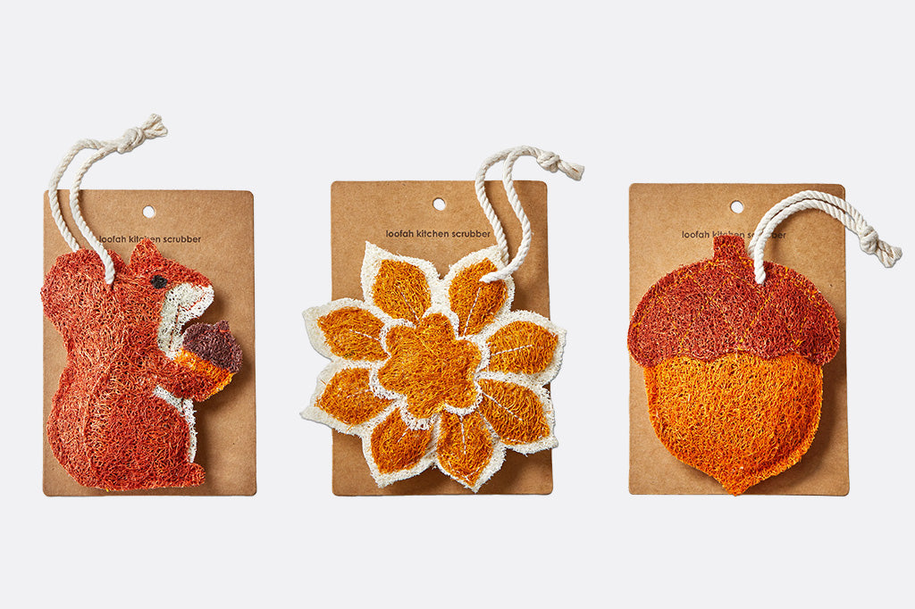 Three knitted scrubbers shaped like a squirrel, flower, and acorn on wooden cards.
