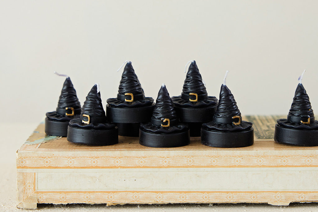 Black witch hat candles on a wooden surface with a neutral background