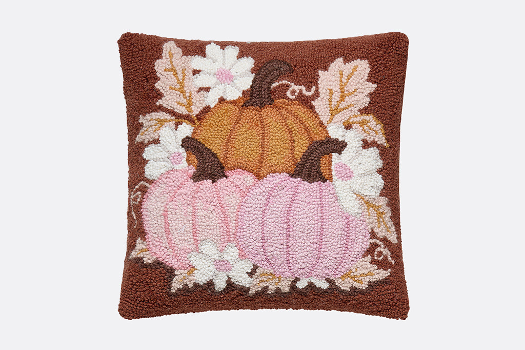 Decorative pillow with pumpkins and leaves on a brown background