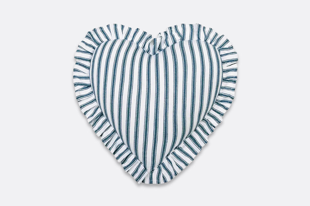 A white ruffle heart shaped pillow with blue stripes.