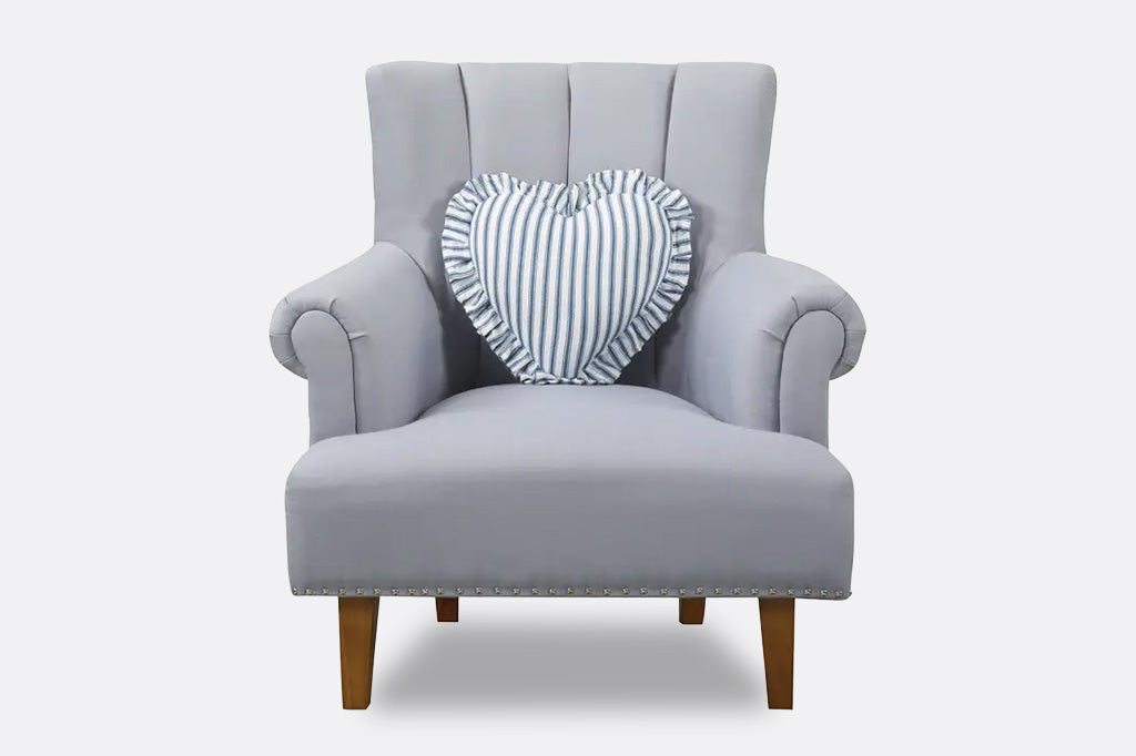 A white ruffle heart shaped pillow with blue stripes.