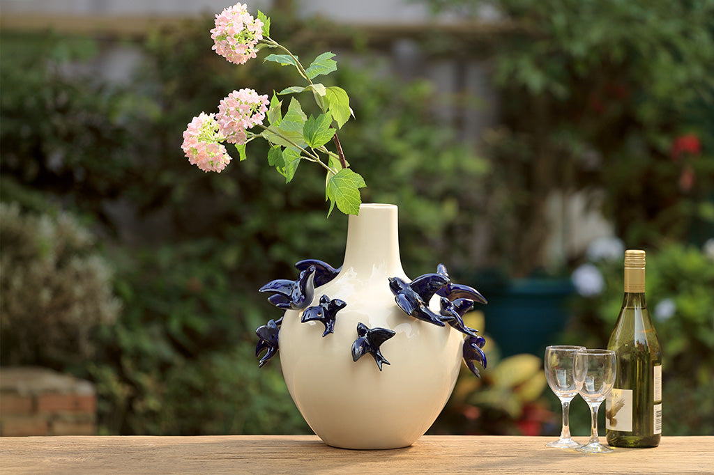A vase of blue birds flying around.