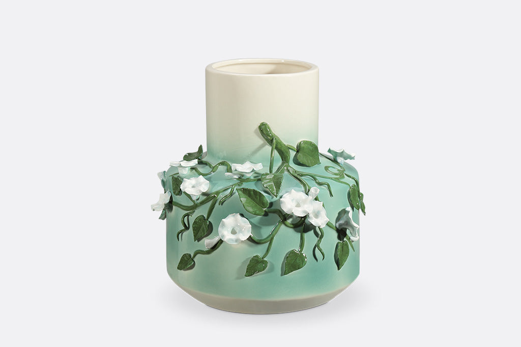 A vase with a green colorway and a design of vines and blossoming flowers.