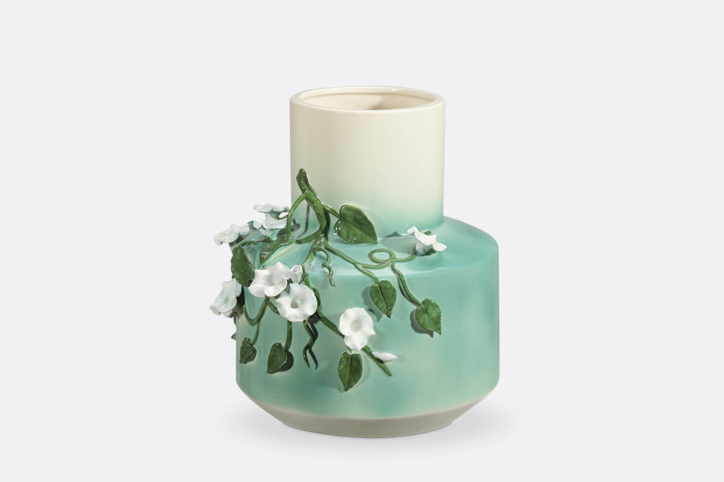 A vase with a green colorway and a design of vines and blossoming flowers.