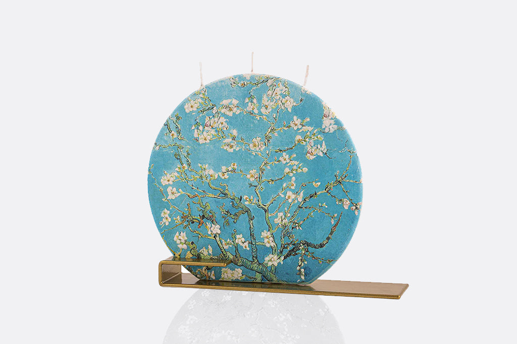 Decorative circular flat candle with floral design on a stand against a white background