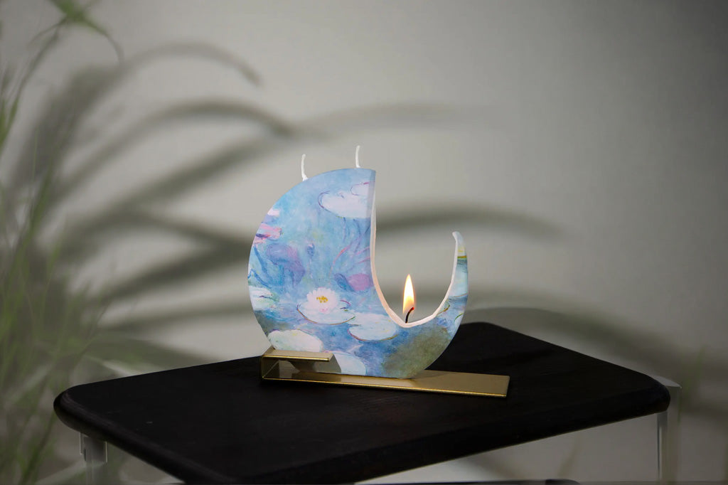 Decorative candle shaped like a moon with a lit candle on a black surface.