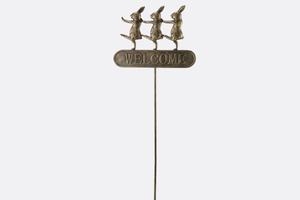 Trio of dancing rabbits decorate a metal staked welcome garden sign