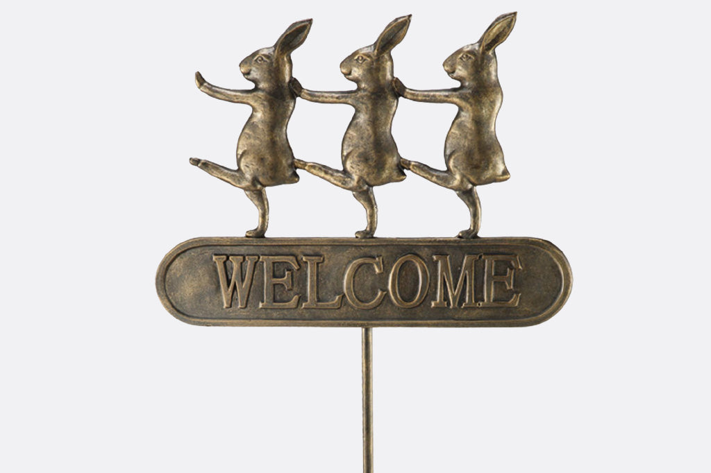 Trio of dancing rabbits decorate a metal staked welcome garden sign