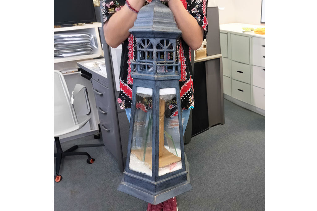 Woman in office holds the Lighthouse Lantern in front of her to show how tall it is.