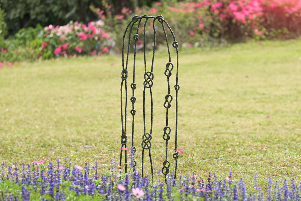 cast metal nautical knots garden trellis set in front of flower bed 