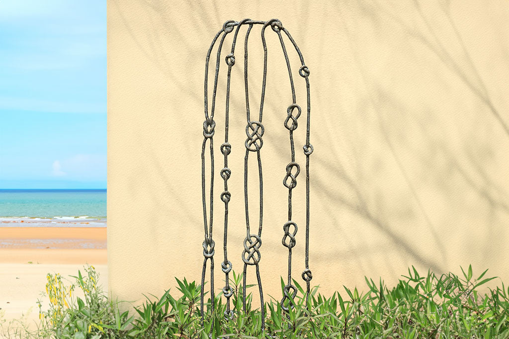 cast metal nautical knots garden trellis set in front of wall on beach