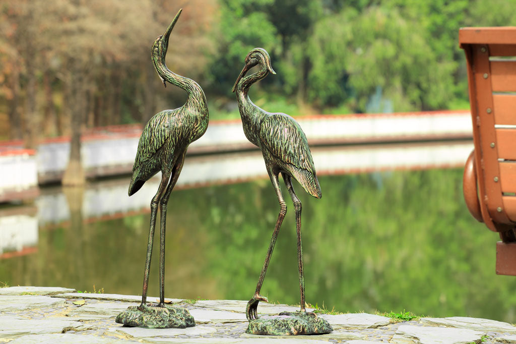 Garden Heron Pair sculpture in front of pond