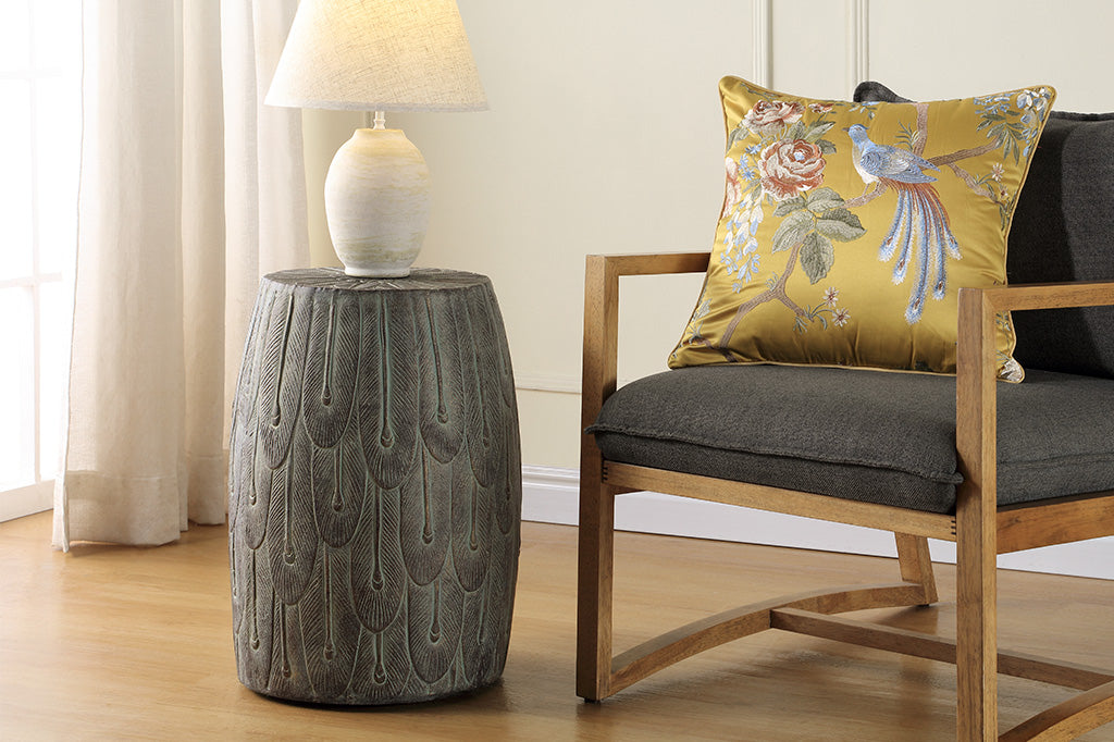 Peacock Feathers Garden Stool shown with lamp in a room with chair and pillow