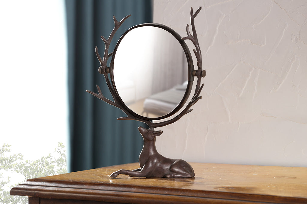 vanity mirror supported by resting deer whose antlers frame the mirror