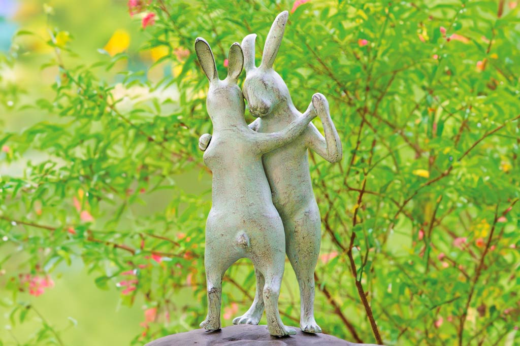 First Dance garden sculpture of two rabbits dancing, posed on a rock in a garden