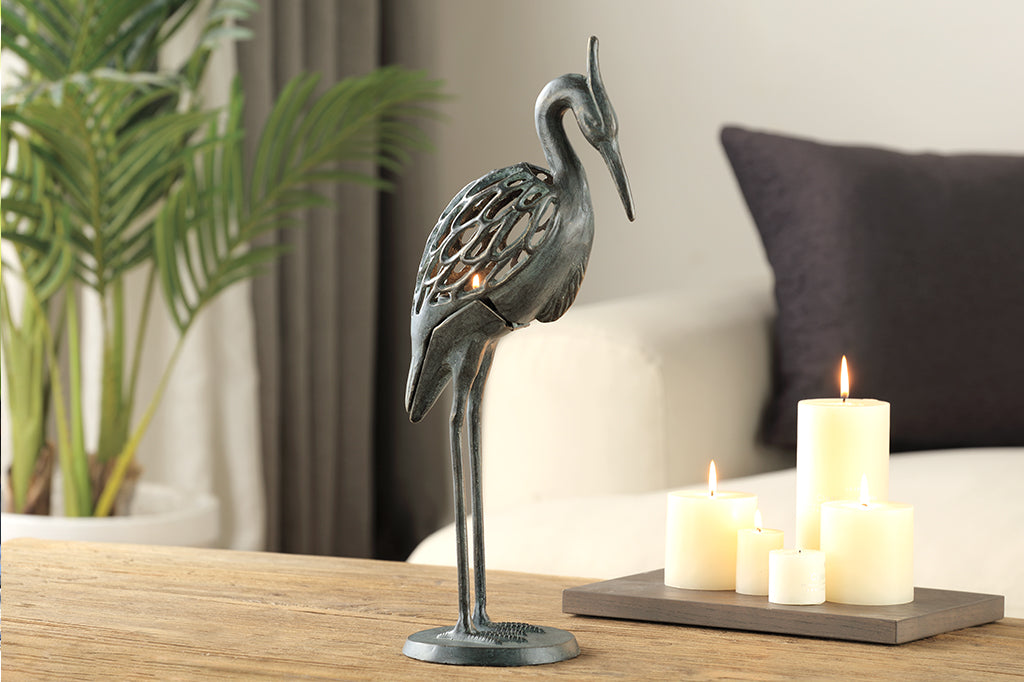 Modern metal heron candleholder with white lit candle 
