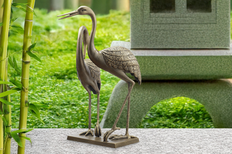 Pensive crane garden sculpture in front of bamboo and pagoda garden sculpture