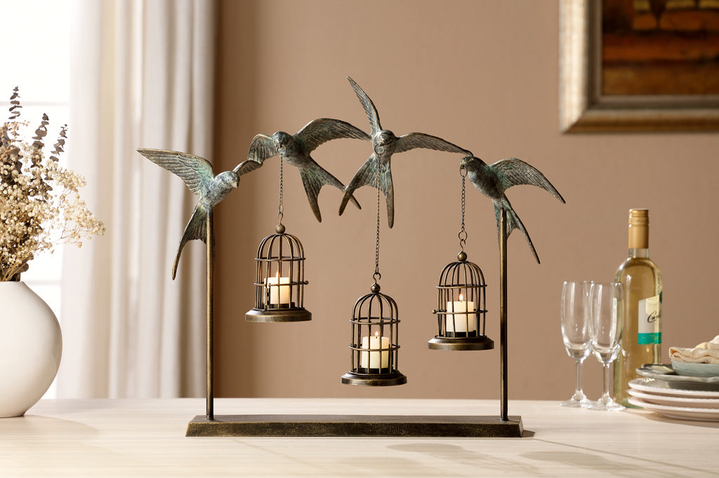 Vuelo de Las Aves hanging lantern table sculpture with 4 sculpted swallows holding 3 candle birdcages. Shown on dining table set with wine and serveware