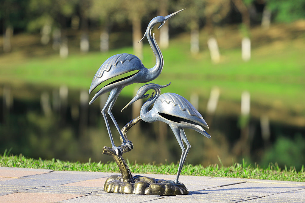two herons one perched on branch while other on rocks garden sculpture designed in a modern geometric style 