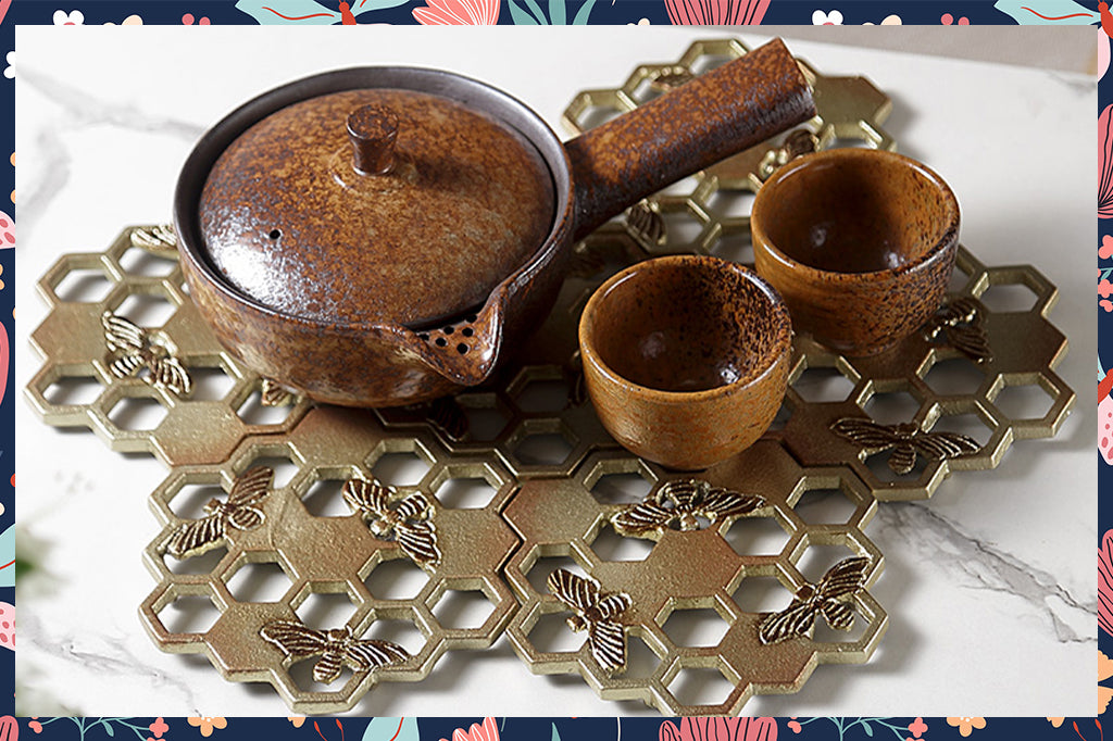 set of six honeycomb and bee metal coasters, shown with ceramic teapot and cups, not included with product purchase