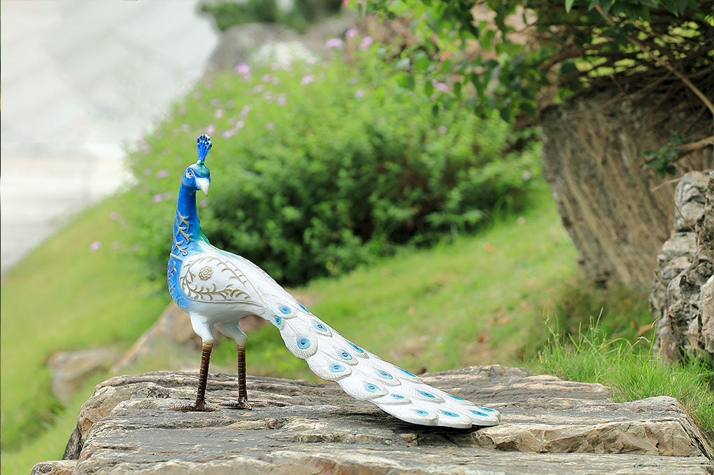 white and blue peacock sculpture shown in garden