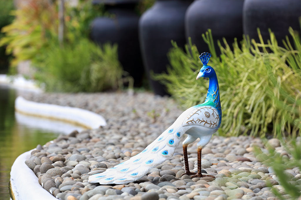 white and blue peacock sculpture shown in garden