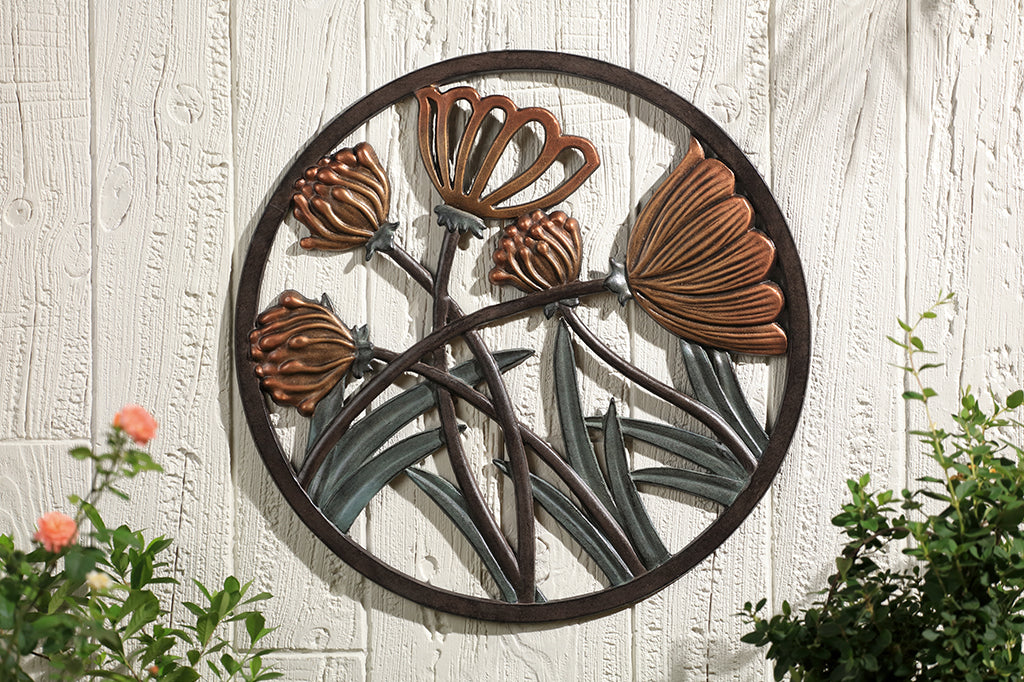 clover and thistle metal wall art placed on wooden wall framed by rose bushes 