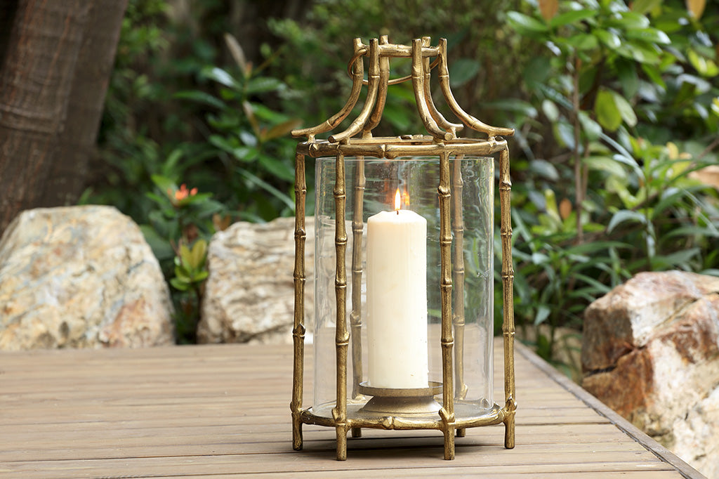 Outdoor metal lantern with bamboo details on deck by rocks and foliage