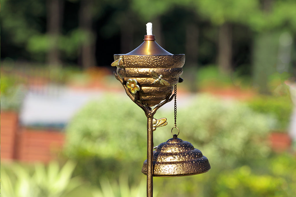 Metal Beehive oil torch with cap off placed in garden 