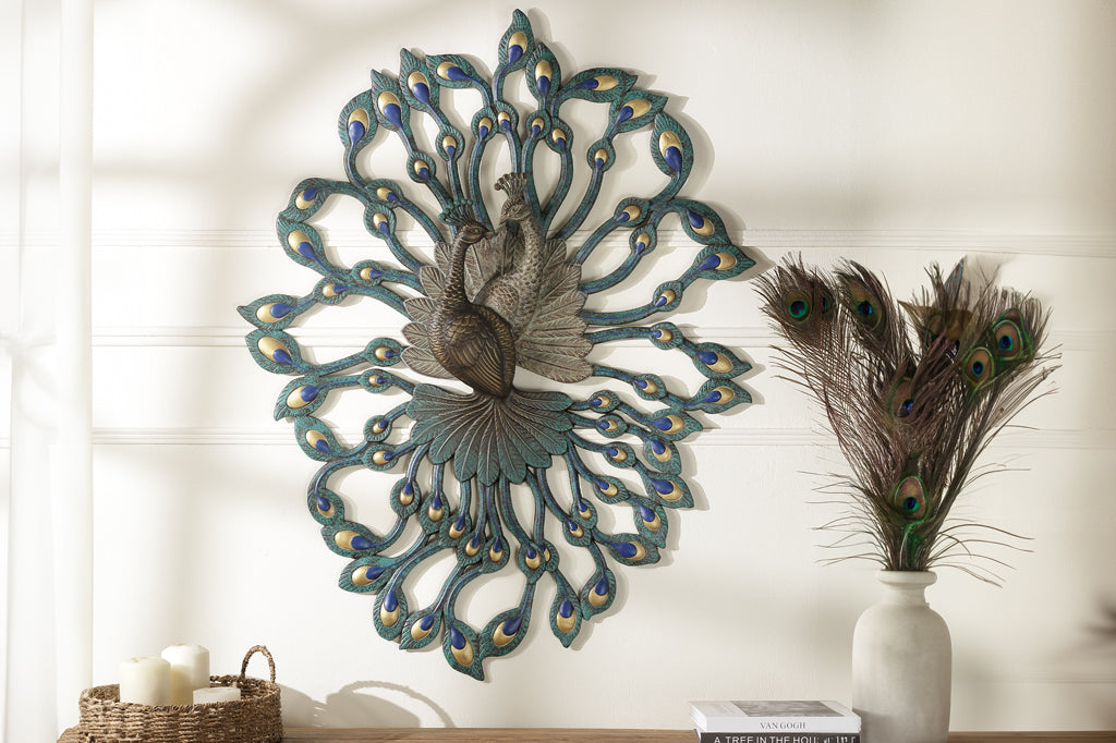 Large peacock wall art shown above wood table indoors, near vase of feathers and basket of candles