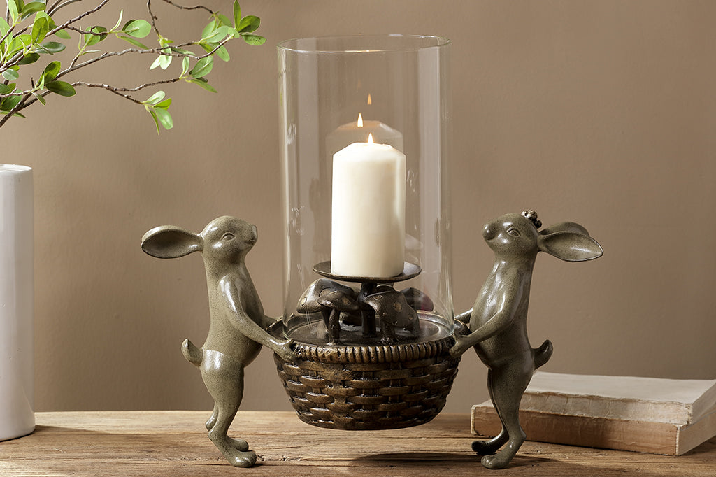 Cast metal bunnies holding a basket candleholder. Small mushroom detail under candle. 