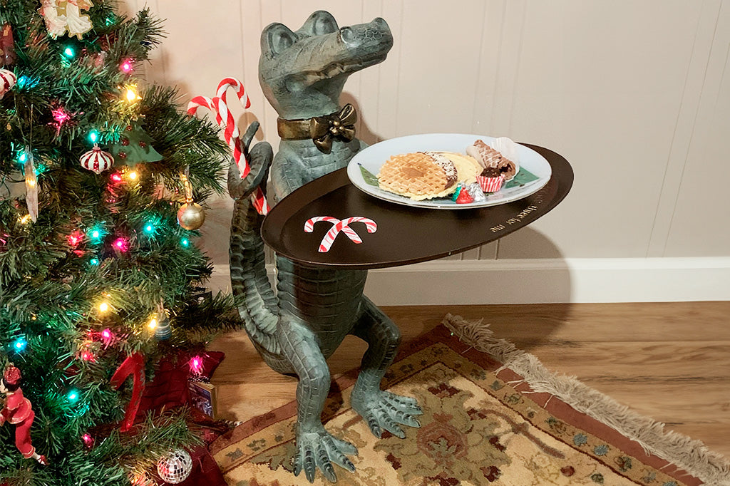 Customer photo of a crocodile butler sculpture holding a tray of cookies in front of a Christmas tree