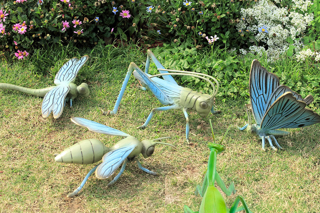 cast metal garden sculpture of grasshopper, shown in flower garden with other metal insect sculptures