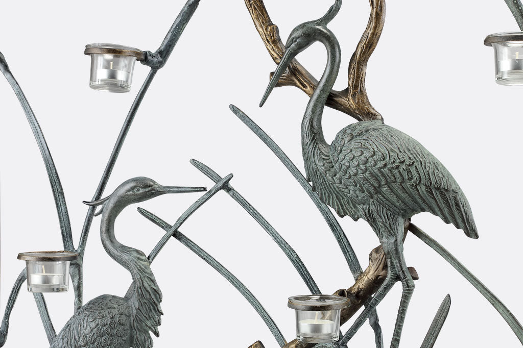 A firescreen with Herons and branches holding tealight candles on a white background