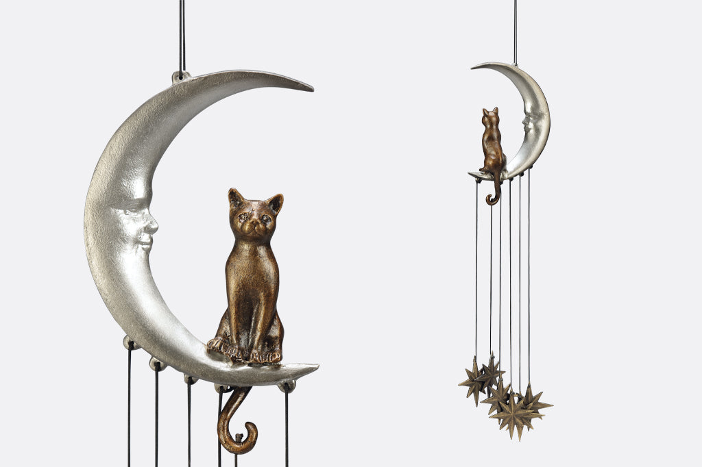 Wind art featuring a cat seated upon a crescent moon with face, 8 point star pendants suspended below.