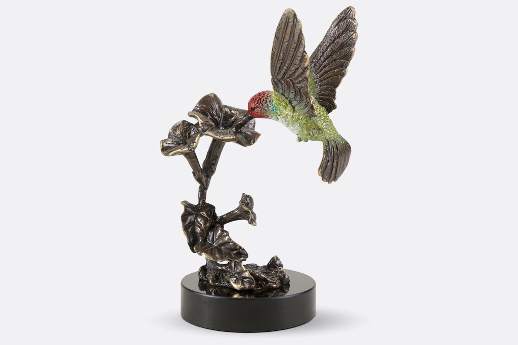 cast metal red and green hummingbirds hovering above flowers