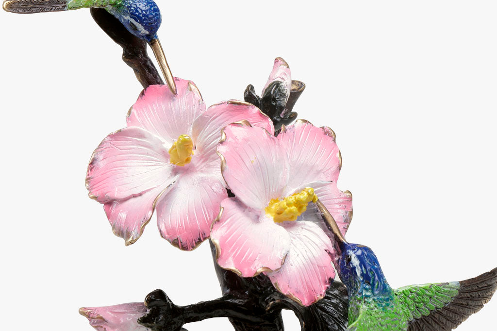 Close up detail of Brass hummingbird sculpture with pink blossoms, indoor sculpture