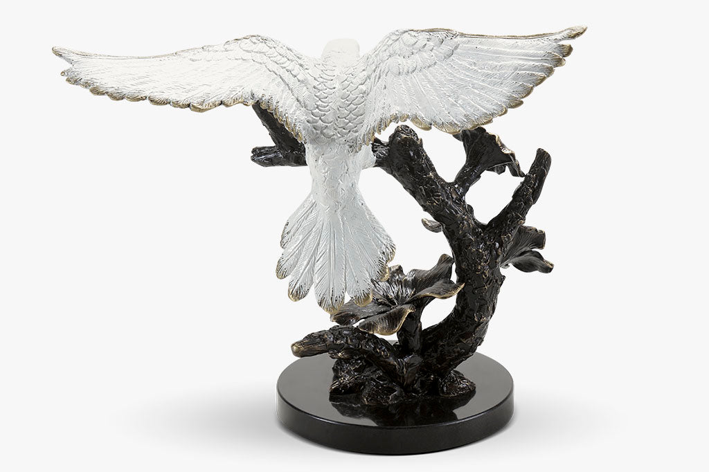 back view of dove, brass sculpture, with outstretched wings on a flowering branch