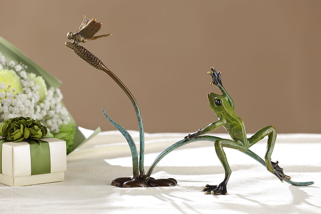 Shown on a table with gifts and flowers, a Cast brass frog and dragonfly on cattail sculpture